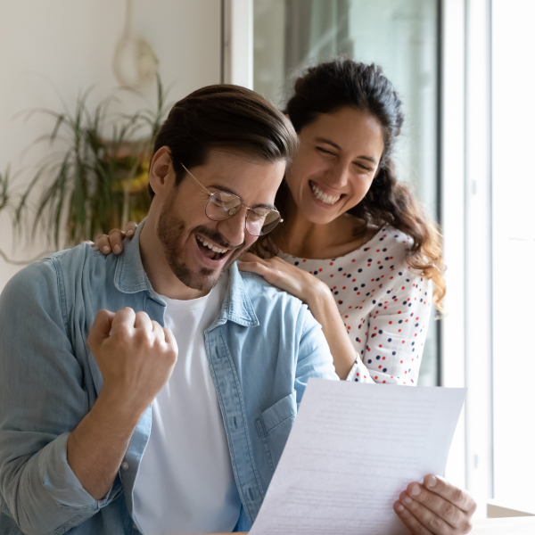 man and woman laughing while reviewing a document together.