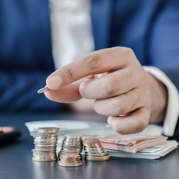 Un homme en costume tient une pièce et compte de l'argent, illustrant sa capacité d'emprunt et sa gestion financière.